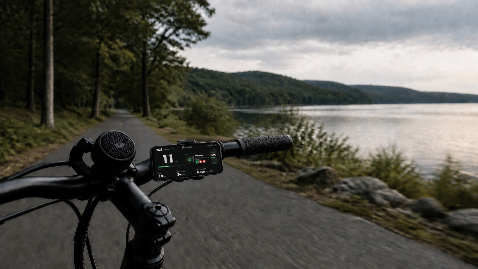 CruiseAmp runs on a handlebar-mounted phone beside a Bluetooth speaker on an e-bike at a lakeside path